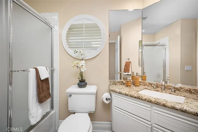 a bathroom with a granite countertop toilet a sink and a mirror