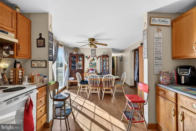 a view of a dining room with furniture one side kitchen view and wooden floor