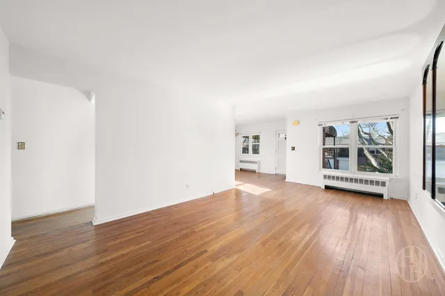 an empty room with wooden floor and window