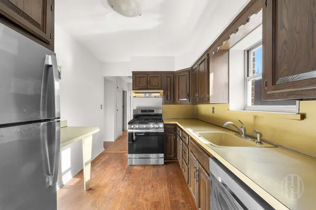 a kitchen with a sink a refrigerator and a stove top oven with wooden floor