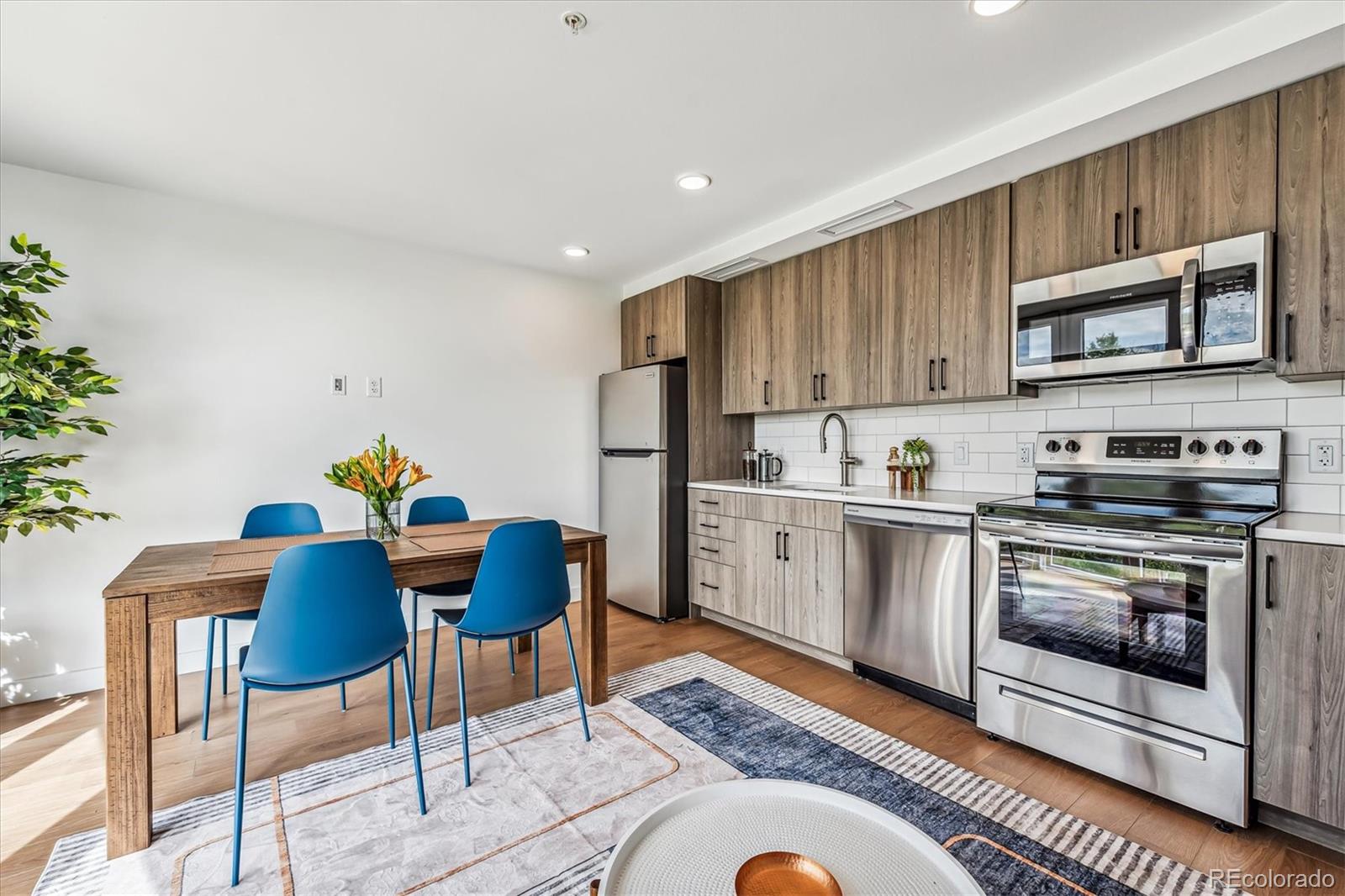 3575 Chestnut Place, Unit 605 Denver, CO 80216 - Photo 6 of 11 a kitchen with stainless steel appliances granite countertop a stove a sink dishwasher a dining table and chairs with wooden floor