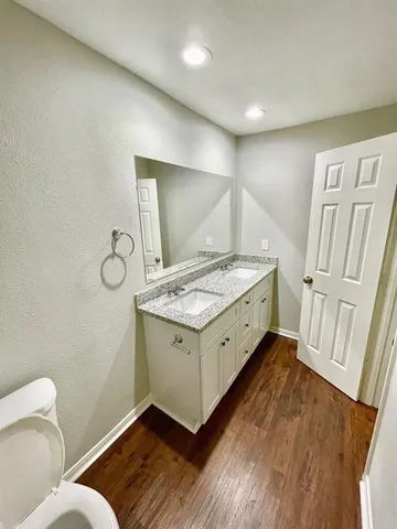a view of an empty room with wooden floor and a ceiling fan