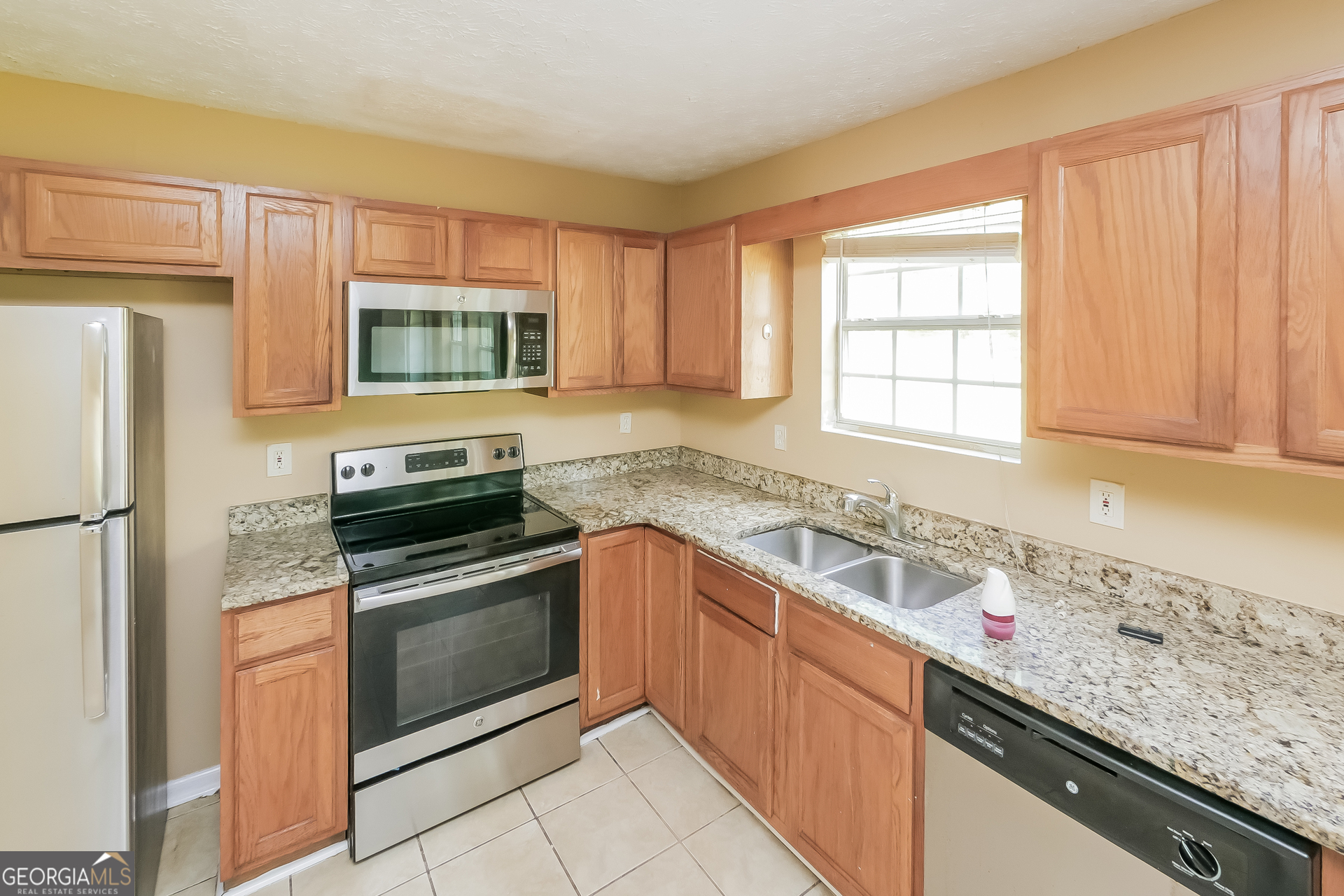 101 Bradesbury Lane Locust Grove, GA 30248 - Photo 5 of 17 a kitchen with stainless steel appliances granite countertop a sink stove and refrigerator