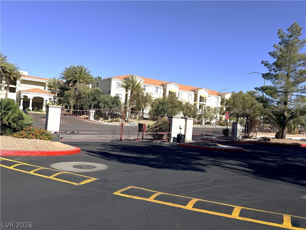 Secure community entrance with iron gates and Mediterranean-inspired architecture beyond.