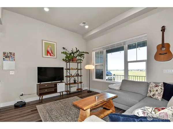 a living room with furniture a flat screen tv and a floor to ceiling window