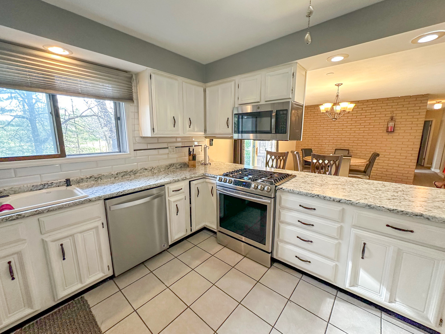 6315 North Post Oak Road Peoria, IL 61615 - Photo 5 of 31 a kitchen with granite countertop white cabinets and white appliances