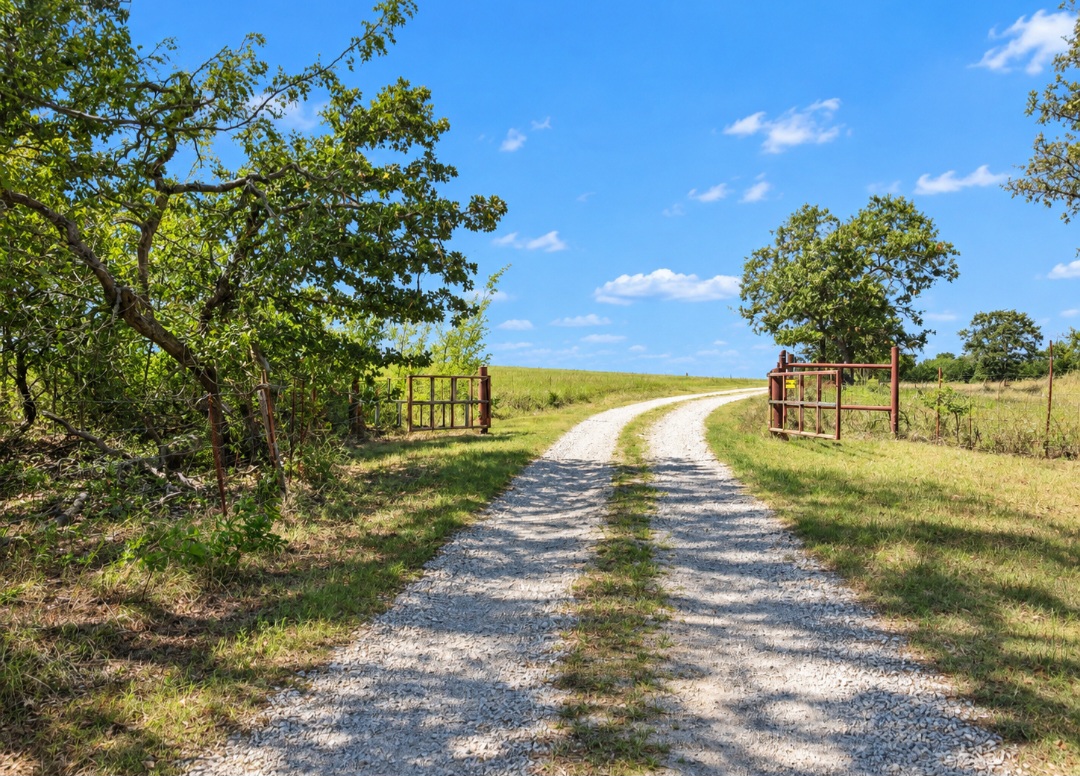 12526 3520th Road Seminole, OK 74868 - Photo 24 of 42 Scenic rural property featuring a long gravel driveway lined with mature oak trees and rustic wooden gates