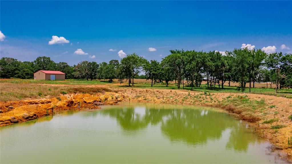 1789 Brumelow Road Whitesboro, TX 76273 - Photo 4 of 30 Private pond with earthen banks and a metal-clad building featuring a red roof
