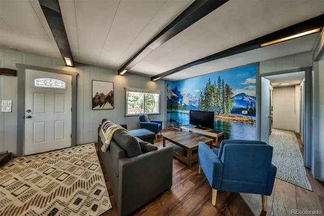 a kitchen with stainless steel appliances kitchen island granite countertop a refrigerator a stove a dining table and chairs with wooden floor