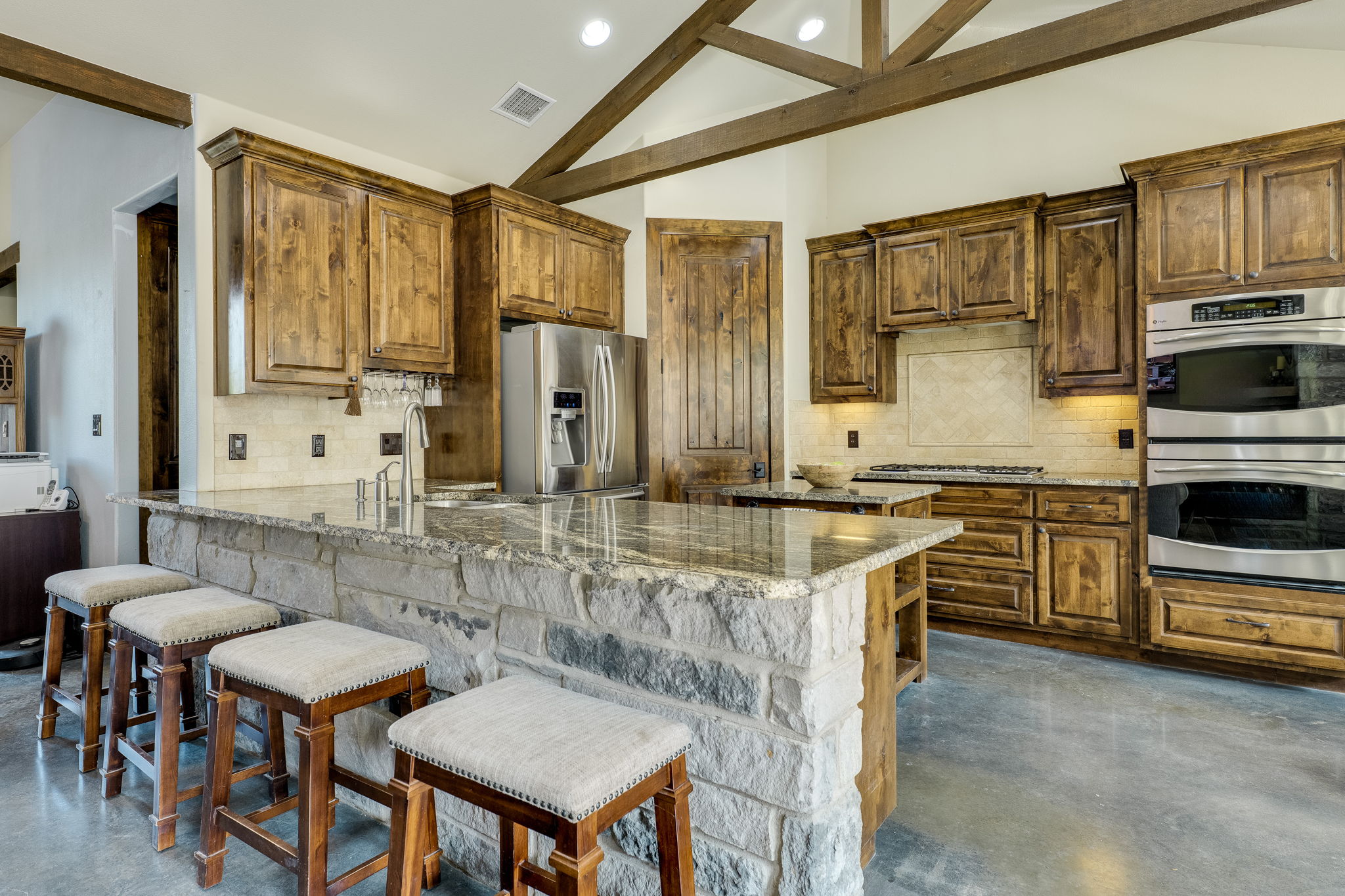 10837 Deer Canyon Road Jonestown, TX 78645 - Photo 4 of 19 a kitchen with stainless steel appliances granite countertop a stove a sink dishwasher a dining table and chairs with wooden floor