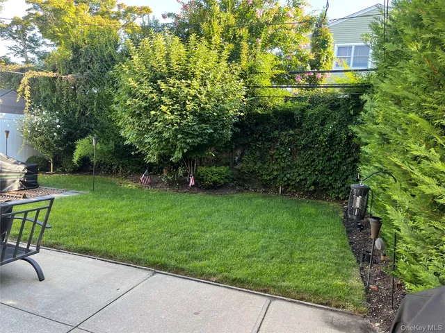 a backyard of a house with table and chairs plants and large trees
