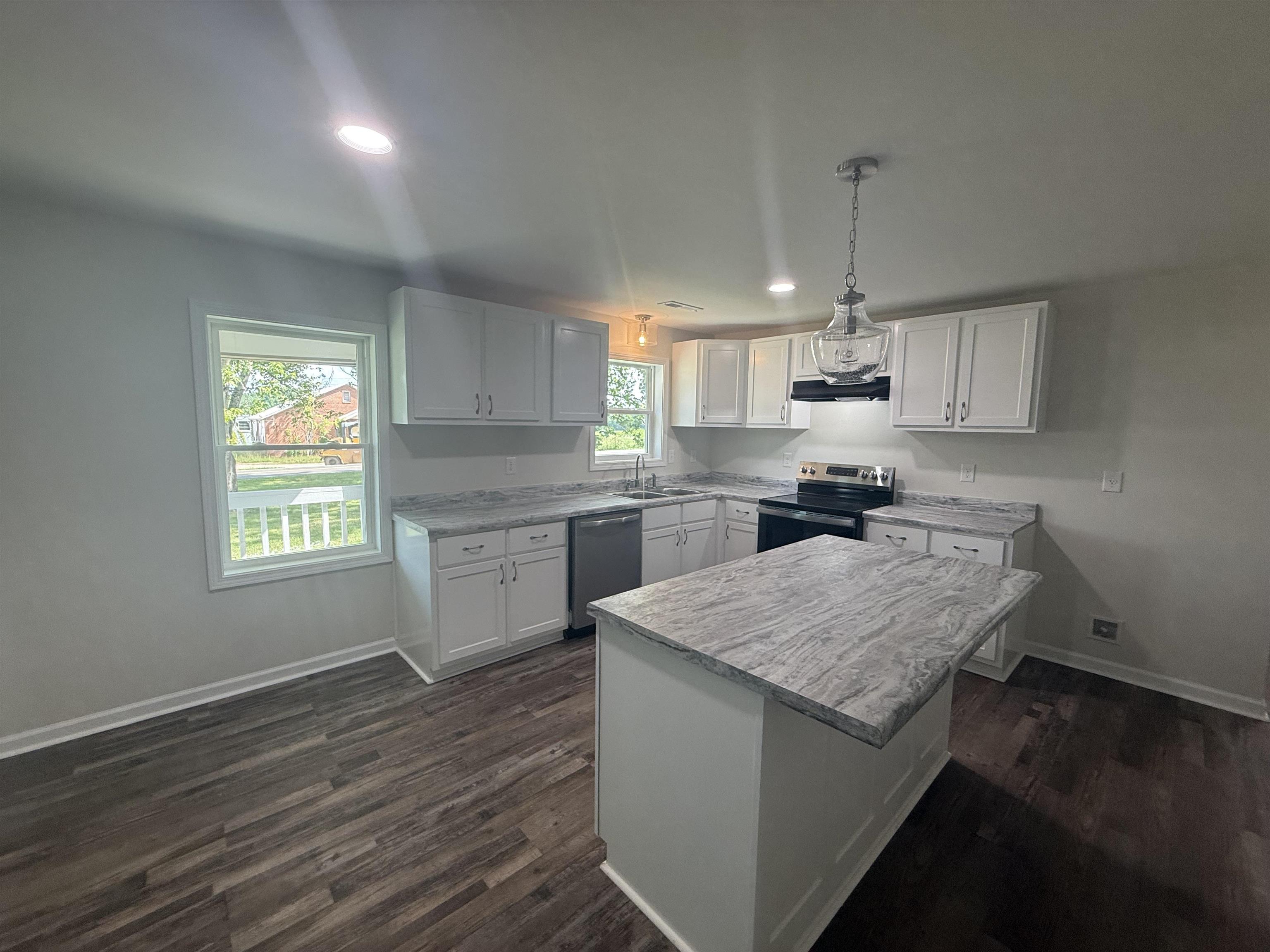 170 Leapwood Road Enville, TN 38332 - Photo 10 of 33 Kitchen featuring an island with a gray patterned countertop, white cabinetry, dark wood-finish flooring, a stainless steel dishwasher, and a black range with an overhead vent