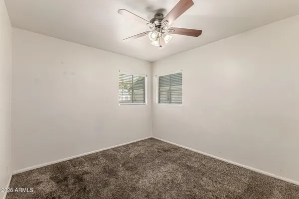 an empty room with windows and fan