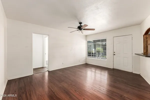 a view of an empty room with wooden floor and a window