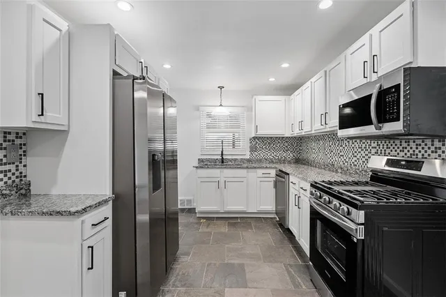 a kitchen with stainless steel appliances granite countertop a stove top oven a sink and a refrigerator