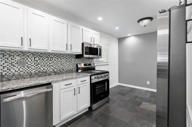 a kitchen with granite countertop cabinets stainless steel appliances and a counter space