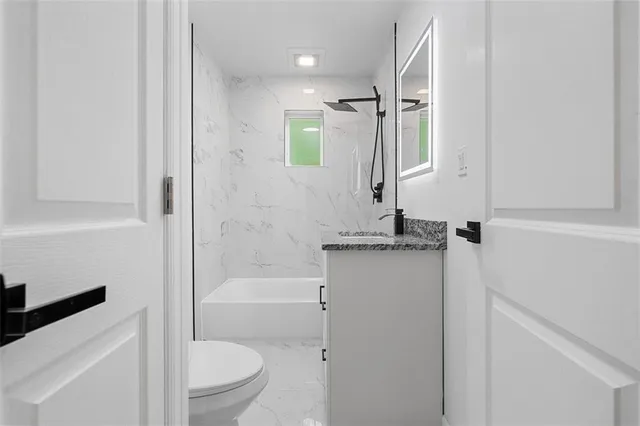 a bathroom with a granite countertop sink toilet and shower