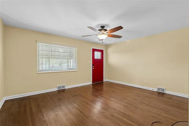 a view of an empty room with wooden floor and a window
