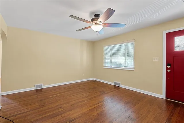 an empty room with wooden floor fan and windows