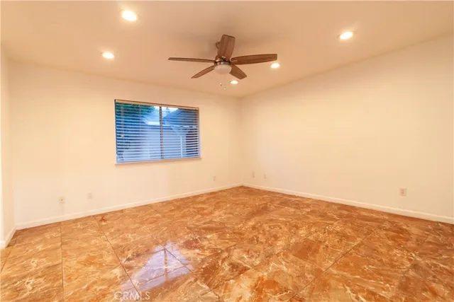 an empty room with a ceiling fan and window