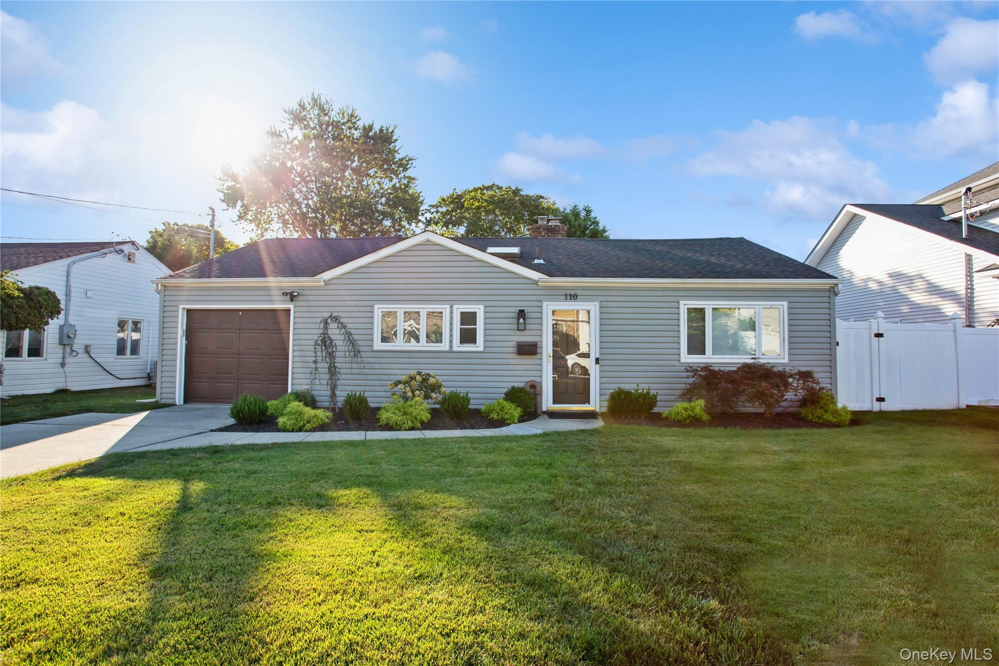Single story home featuring driveway, an attached garage, a chimney, and a shingled roof