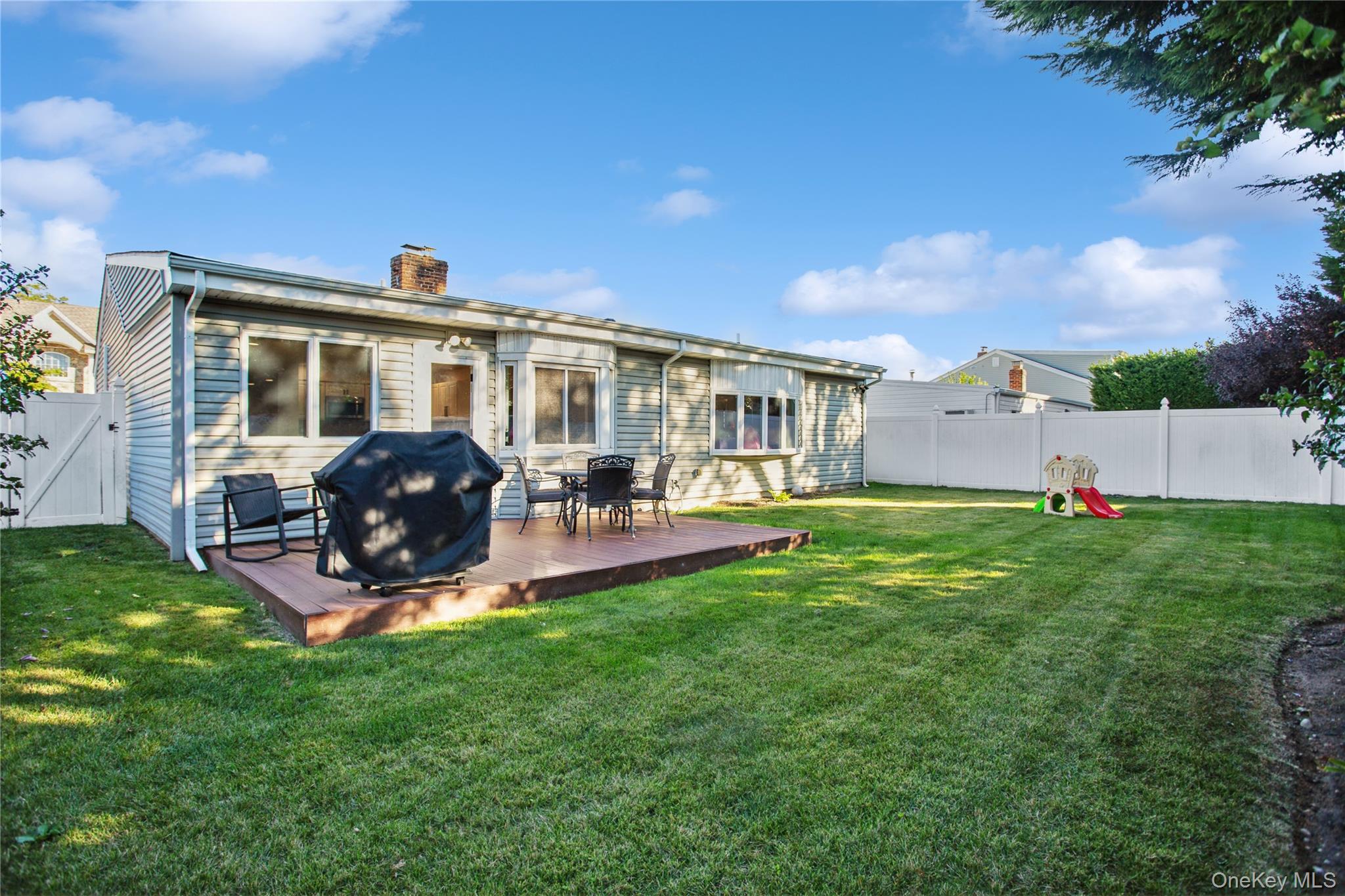 110 Hampton Way Merrick, NY 11566 - Photo 22 of 24 Back of property with a fenced backyard, a chimney, and a deck
