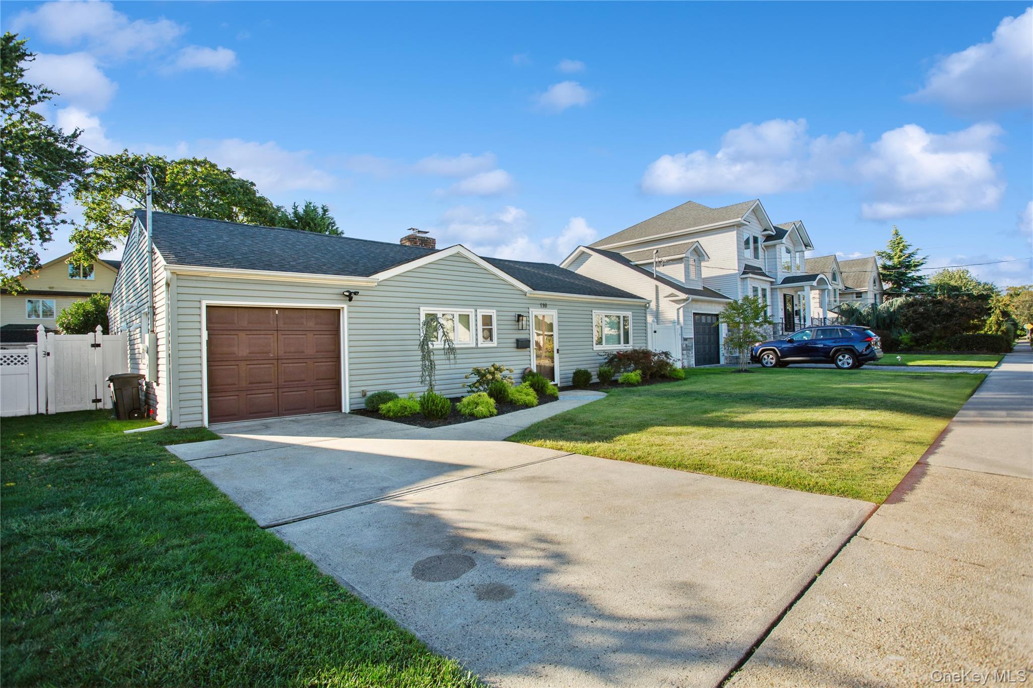 110 Hampton Way Merrick, NY 11566 - Photo 24 of 24 Traditional-style house with concrete driveway, a gate, an attached garage, a shingled roof, and a chimney