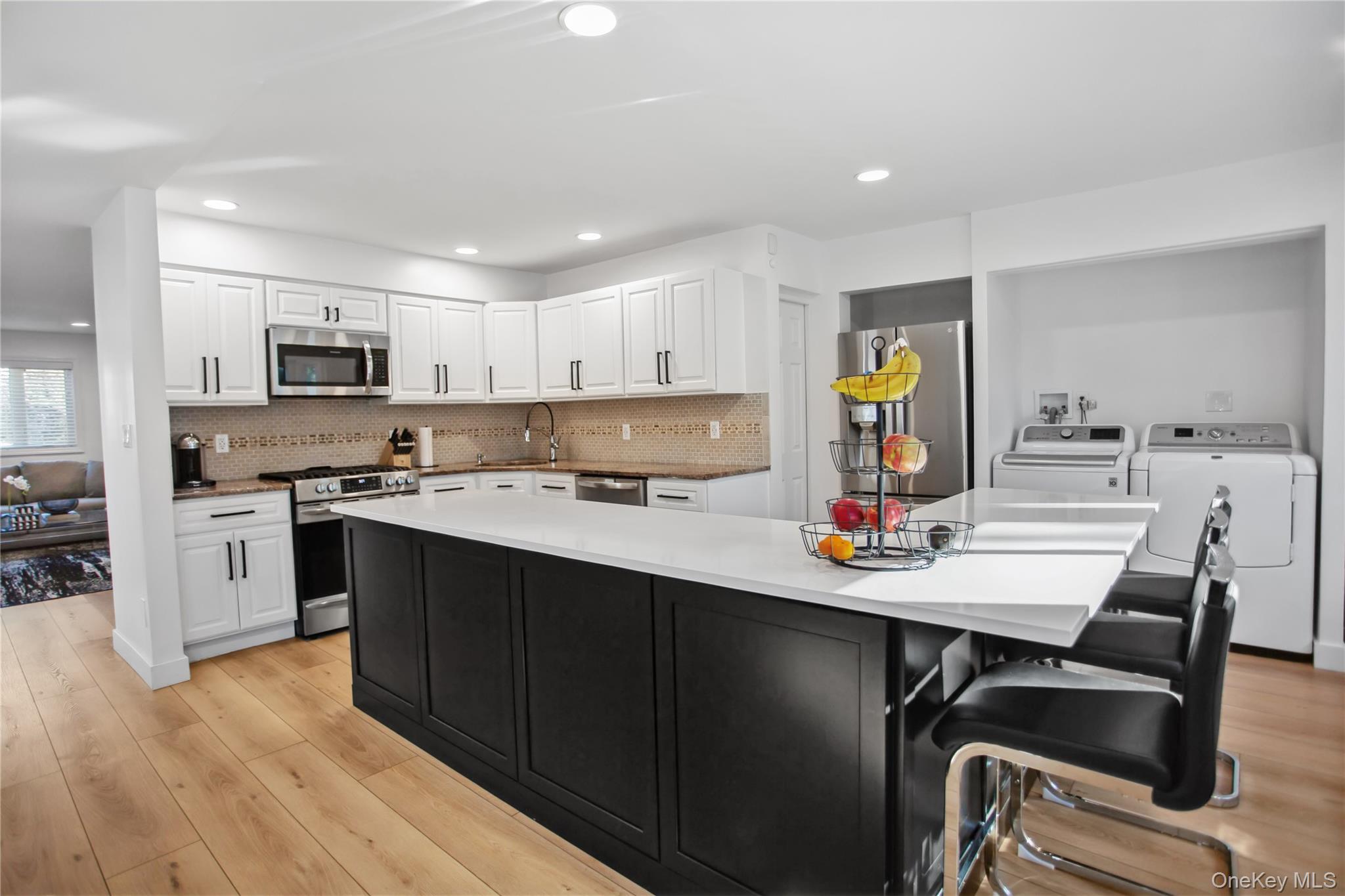 110 Hampton Way Merrick, NY 11566 - Photo 4 of 24 Kitchen featuring dark cabinets, white cabinets, appliances with stainless steel finishes, light wood-type flooring, and recessed lighting