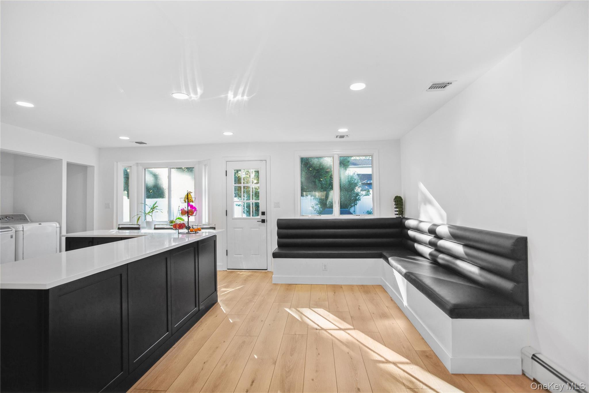110 Hampton Way Merrick, NY 11566 - Photo 6 of 24 Kitchen with dark cabinetry, baseboard heating, healthy amount of natural light, light wood-style flooring, and recessed lighting