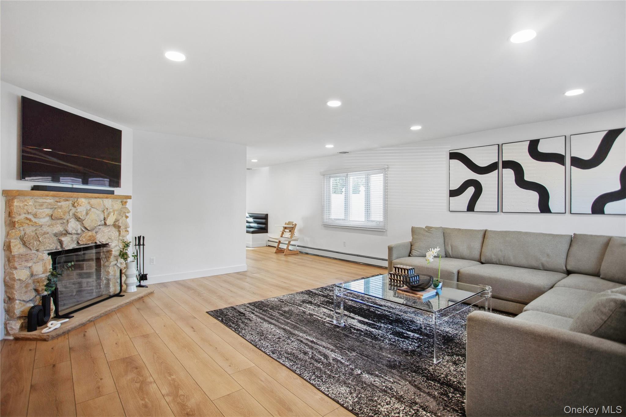 110 Hampton Way Merrick, NY 11566 - Photo 10 of 24 Living room with recessed lighting, light wood-type flooring, a baseboard heating unit, and a fireplace