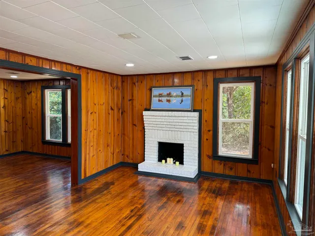 a view of an empty room with wooden floor fireplace and a window