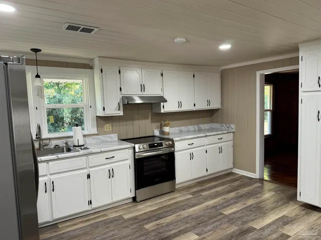 a kitchen with stainless steel appliances granite countertop a sink refrigerator and window