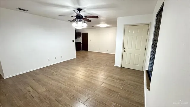 an empty room with wooden floor and a ceiling fan