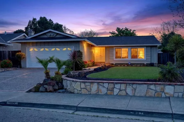 a front view of a house with a yard and potted plants