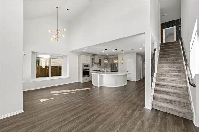 a view of an empty room with wooden floor and staircase
