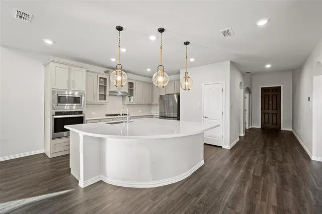 a large white kitchen with wooden floor