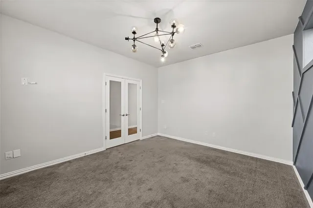 a view of an empty room with a chandelier fan