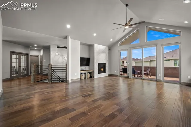a view of an empty room with wooden floor kitchen view and a window