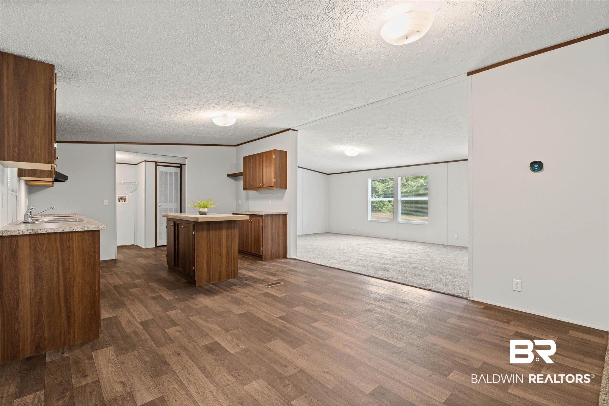 25366 Pollard Road Daphne, AL 36526 - Photo 10 of 22 Open-concept living space featuring wood-finish flooring, a kitchen island, integrated sink, overhead lighting, and white walls
