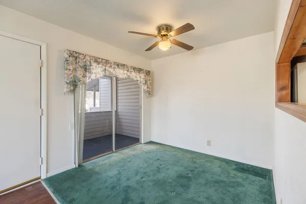 an empty room with windows and fan