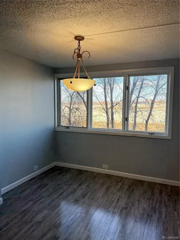 an empty room with wooden floor chandelier and windows