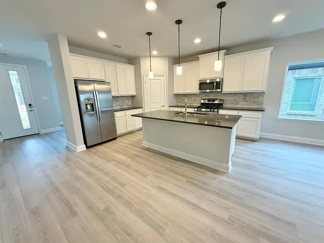 a kitchen with stainless steel appliances granite countertop a refrigerator a stove a sink and a oven