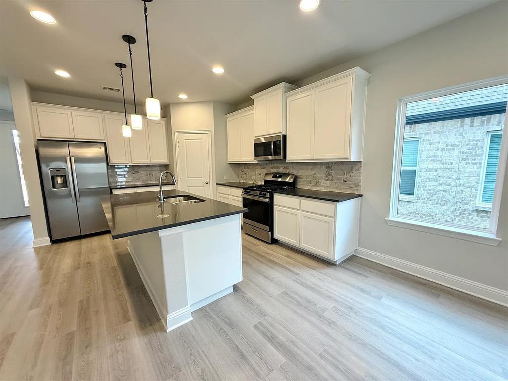 2708 Shiners Street Forney, TX 75126 - Photo 8 of 25 a kitchen with stainless steel appliances granite countertop a stove a sink dishwasher a refrigerator and white cabinets with wooden floor