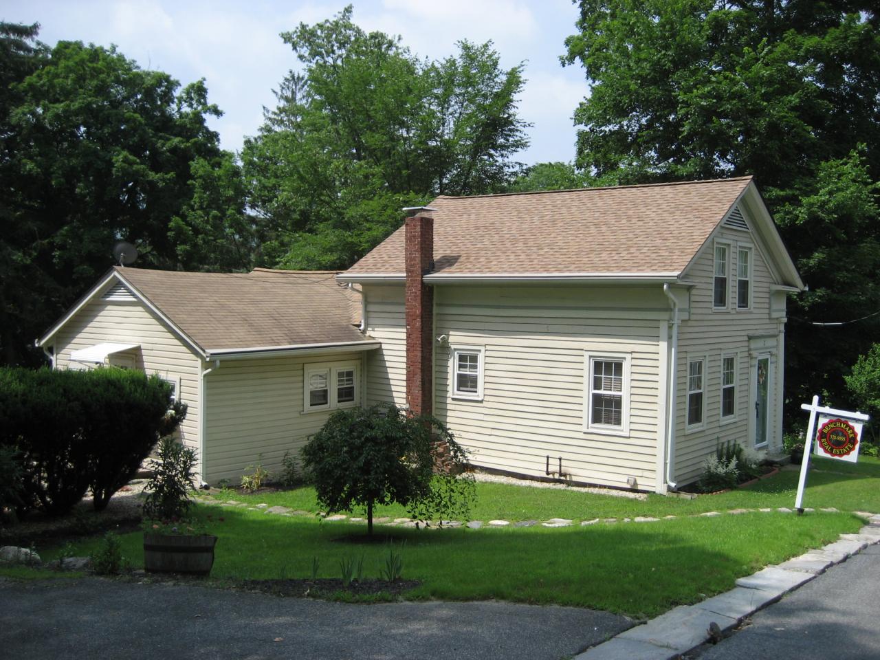 a view of a yard in front of a house with plants and large tree