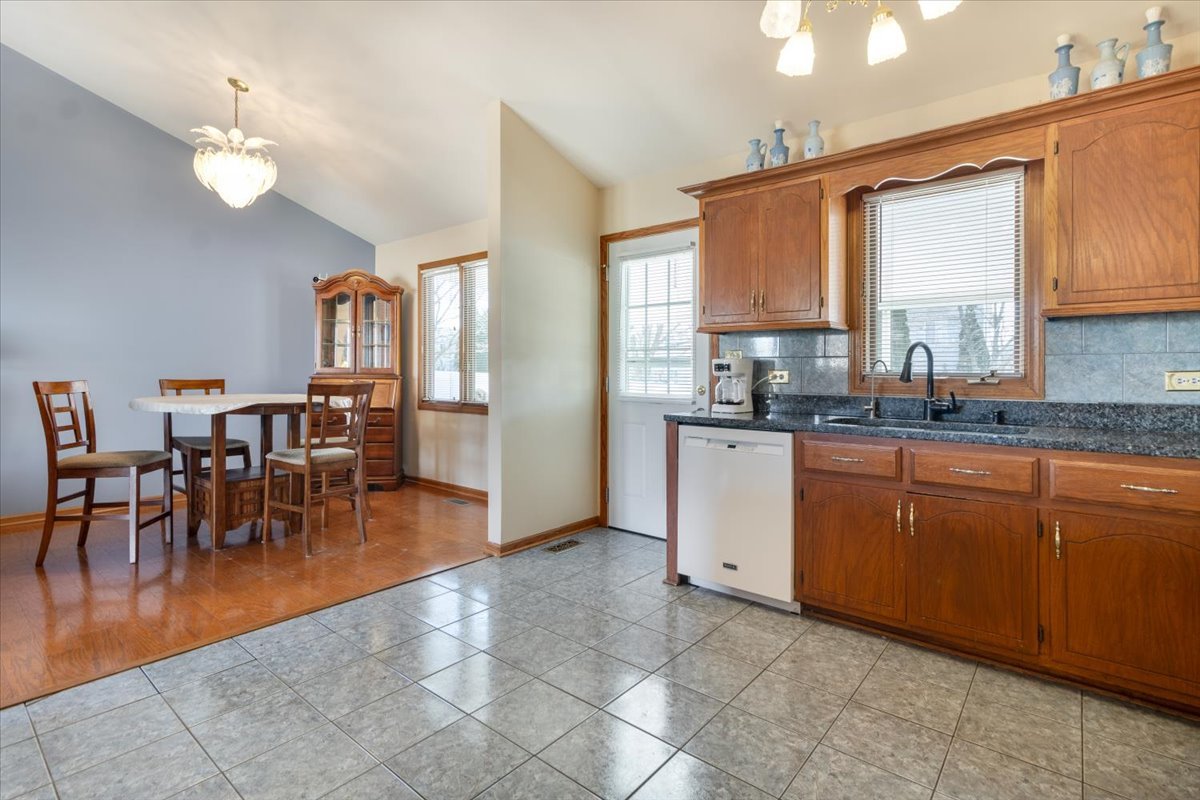 16641 West Oneida Drive Lockport, IL 60441 - Photo 10 of 24 a kitchen with granite countertop a stove a sink a dining table and chairs