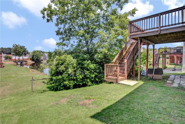 a view of a deck that has lawn chairs and a yard with wooden fence