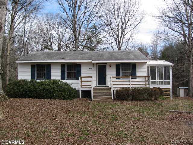 a front view of house with yard and trees in the background