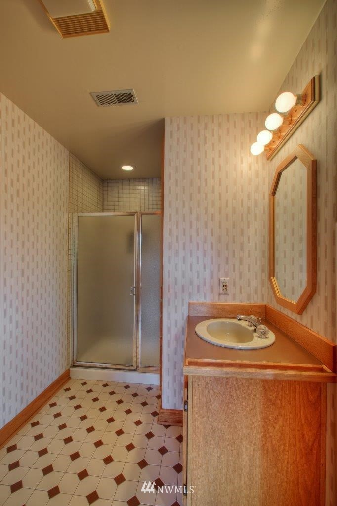 1822 Channel Road East Lake Tapps, WA 98391 - Photo 23 of 38 a bathroom with a sink a mirror and a shower