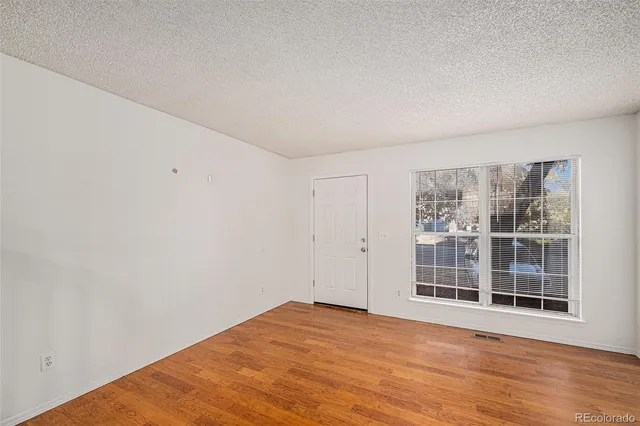 an empty room with wooden floor fireplace and windows