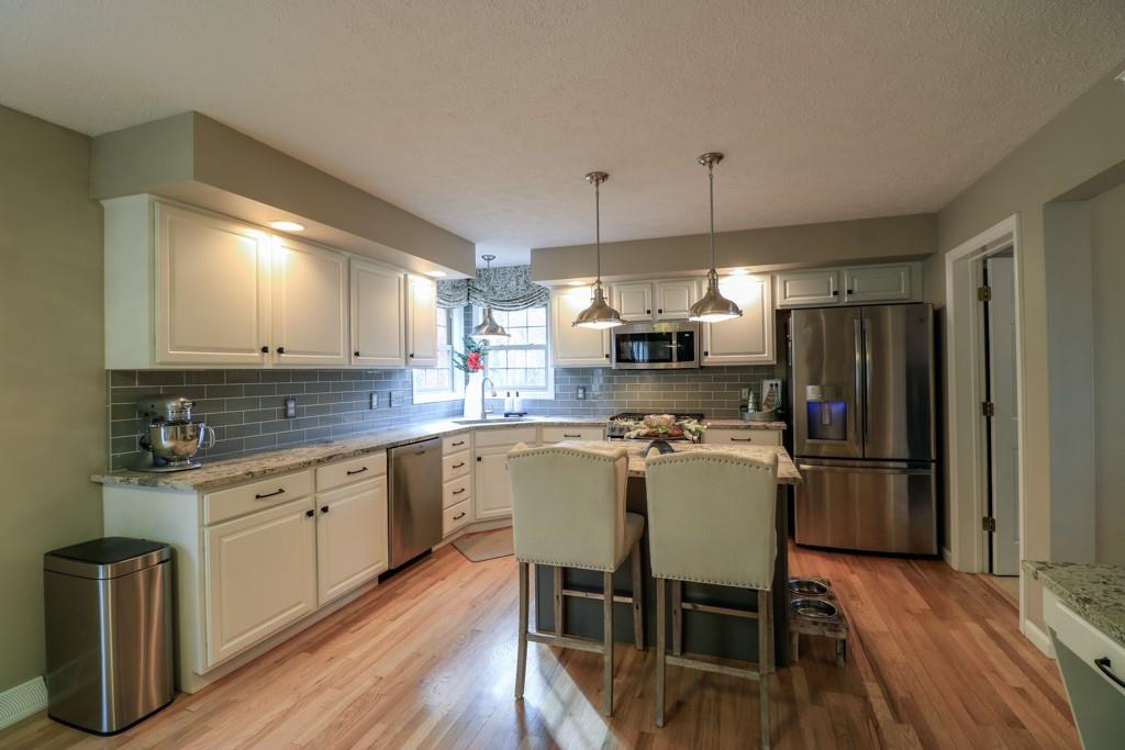 549 Dorchester Drive Seven Fields, PA 16046 - Photo 7 of 35 a kitchen with a dining table chairs wooden floor cabinets appliances and a window
